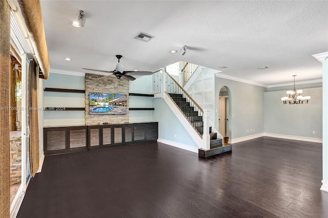 unfurnished living room with a healthy amount of sunlight, dark wood-type flooring, a textured ceiling, ceiling fan with notable chandelier, and ornamental molding