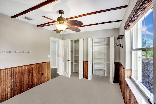 unfurnished bedroom featuring carpet, a textured ceiling, ceiling fan, and wooden walls