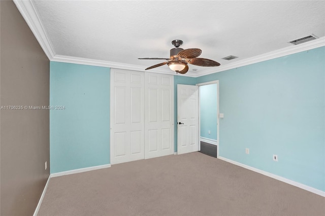 unfurnished bedroom with carpet flooring, ceiling fan, ornamental molding, and a textured ceiling