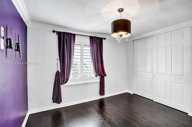 spare room featuring dark hardwood / wood-style flooring, a textured ceiling, and ornamental molding