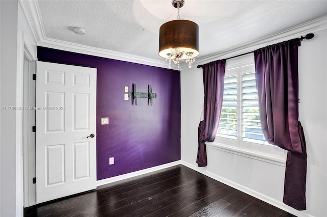 spare room with a textured ceiling, an inviting chandelier, dark hardwood / wood-style floors, and ornamental molding