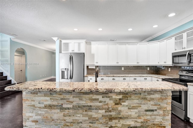 kitchen featuring backsplash, a center island with sink, white cabinets, appliances with stainless steel finishes, and light stone counters