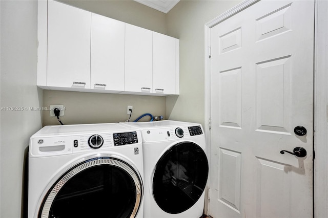 clothes washing area with crown molding, washer and clothes dryer, and cabinets