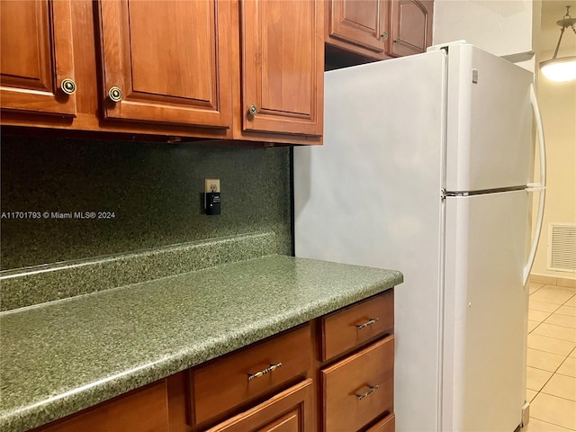 kitchen with light tile patterned floors, white fridge, and tasteful backsplash