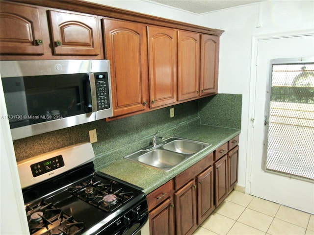 kitchen with light tile patterned flooring, black range with gas stovetop, and sink