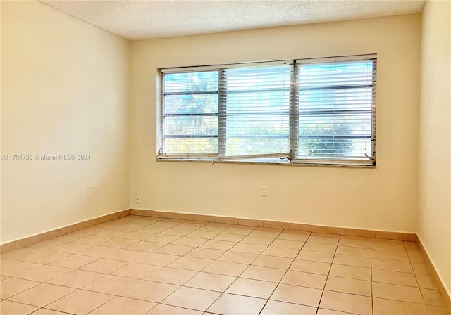 spare room with light tile patterned floors and a textured ceiling