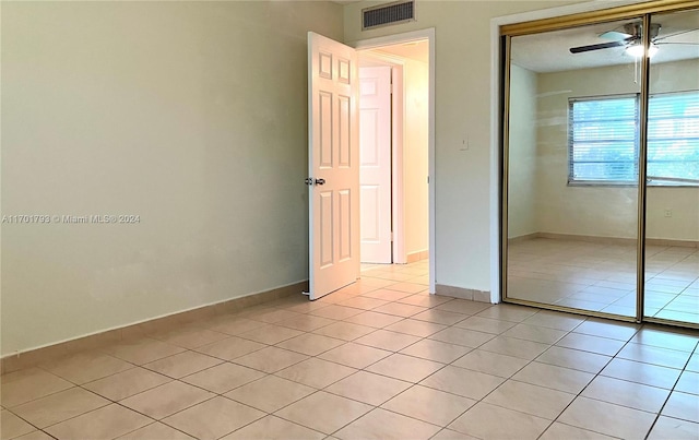 unfurnished bedroom with ceiling fan, a closet, and light tile patterned flooring