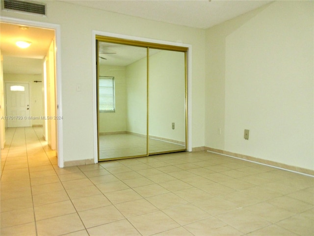 unfurnished bedroom featuring light tile patterned floors and a closet