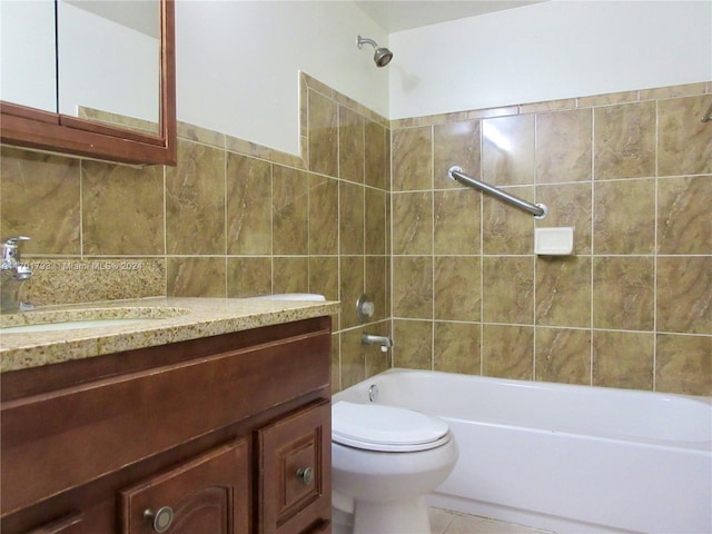 full bathroom featuring vanity, tile patterned floors, tiled shower / bath combo, toilet, and tile walls