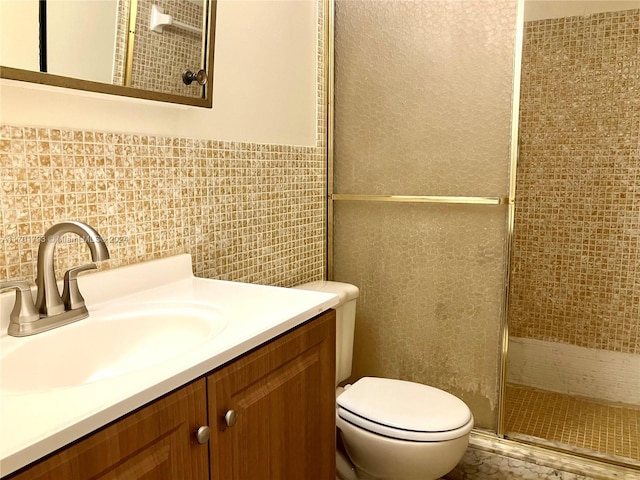 bathroom with vanity, toilet, a shower with door, and tile walls