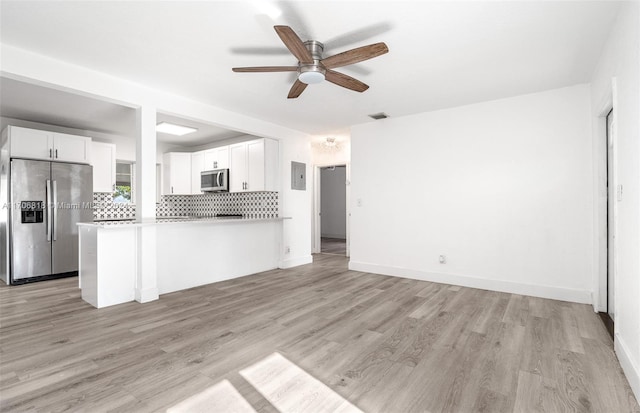 kitchen with kitchen peninsula, appliances with stainless steel finishes, light wood-type flooring, and white cabinetry