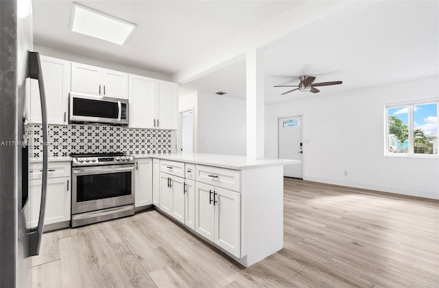 kitchen with kitchen peninsula, stainless steel appliances, white cabinetry, and light hardwood / wood-style floors