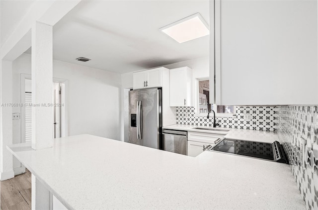 kitchen featuring sink, stainless steel appliances, backsplash, kitchen peninsula, and white cabinets