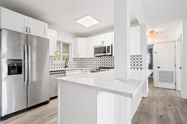 kitchen featuring light stone countertops, white cabinetry, stainless steel appliances, and light hardwood / wood-style flooring