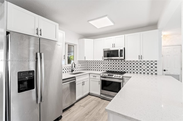 kitchen with sink, tasteful backsplash, light hardwood / wood-style floors, white cabinetry, and stainless steel appliances