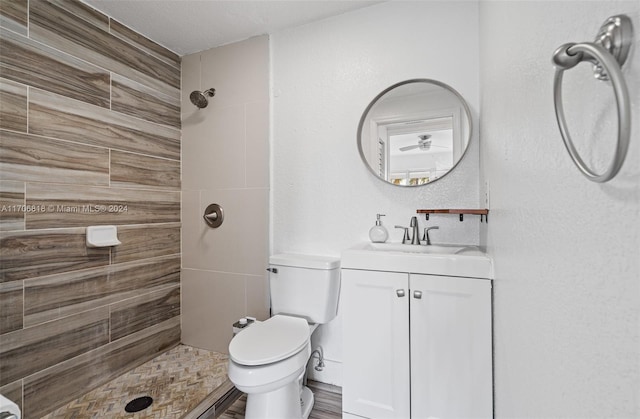 bathroom featuring a tile shower, vanity, and toilet