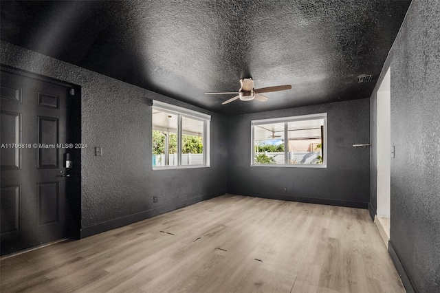 unfurnished room featuring ceiling fan, light hardwood / wood-style flooring, and a textured ceiling