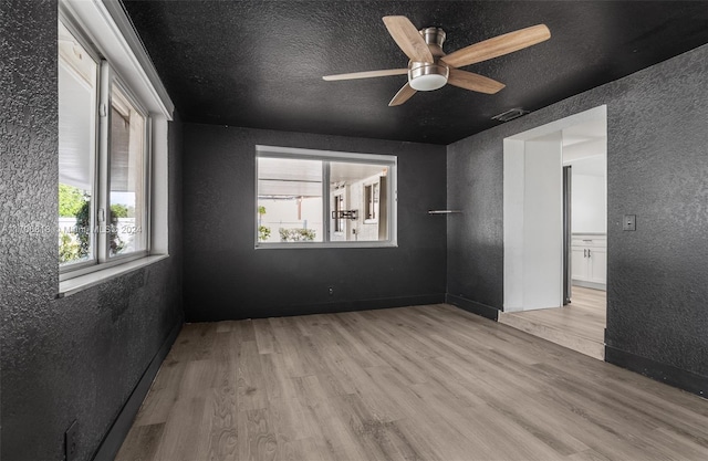 spare room featuring ceiling fan, light hardwood / wood-style floors, and a textured ceiling