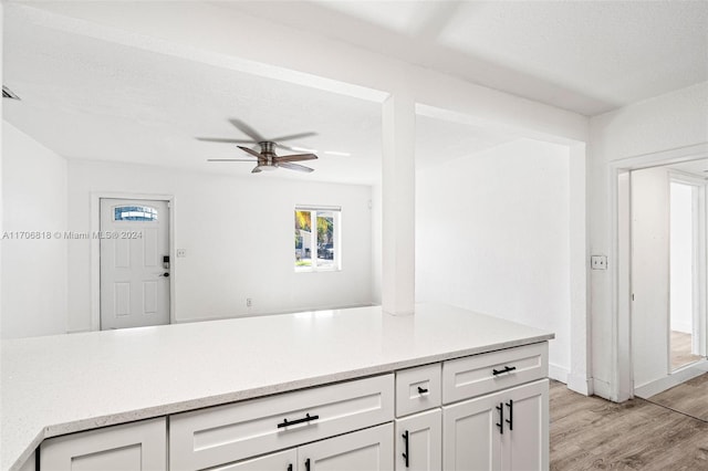 kitchen with white cabinets, ceiling fan, a textured ceiling, and light hardwood / wood-style flooring