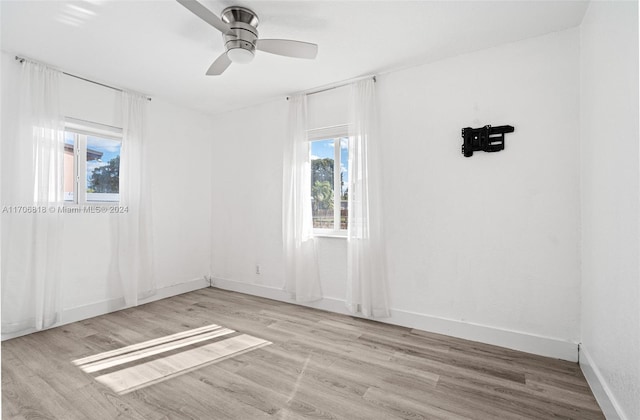 empty room with plenty of natural light, light hardwood / wood-style floors, and ceiling fan