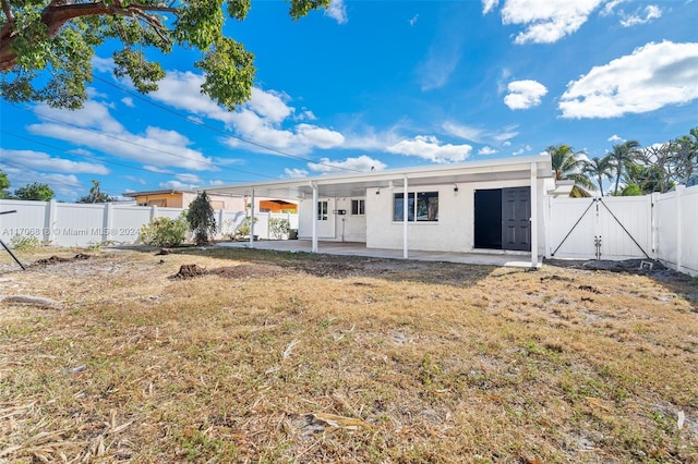 rear view of house featuring a lawn and a patio