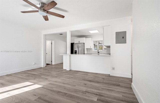 unfurnished living room with electric panel, ceiling fan, and light wood-type flooring