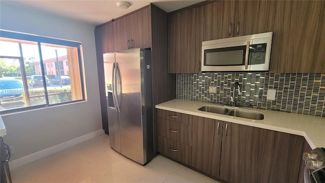 kitchen featuring backsplash, stainless steel appliances, dark brown cabinetry, and sink