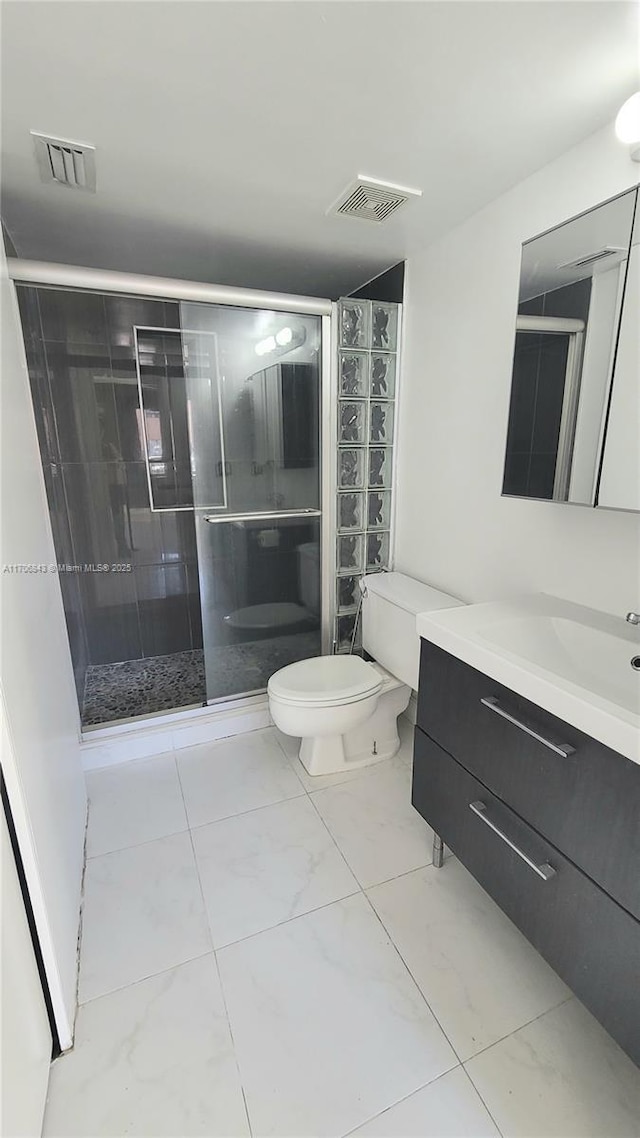 bathroom featuring a shower with door, vanity, and toilet