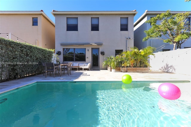 rear view of property featuring a patio area, a fenced in pool, and an outdoor hangout area