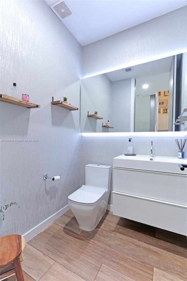 bathroom with hardwood / wood-style floors, vanity, and toilet