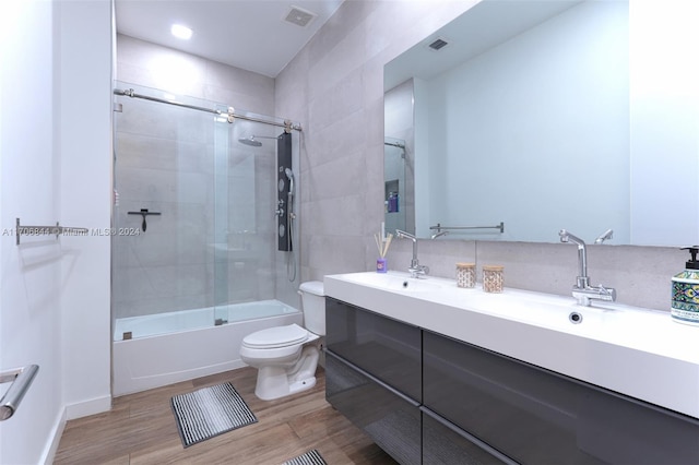 full bathroom featuring shower / bath combination with glass door, hardwood / wood-style floors, vanity, and toilet