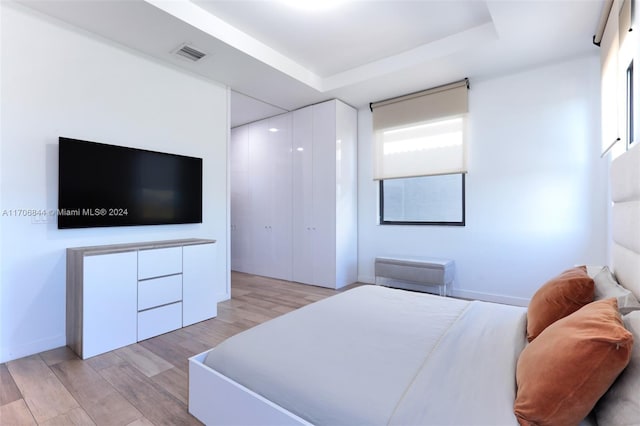 bedroom featuring a tray ceiling and light hardwood / wood-style flooring