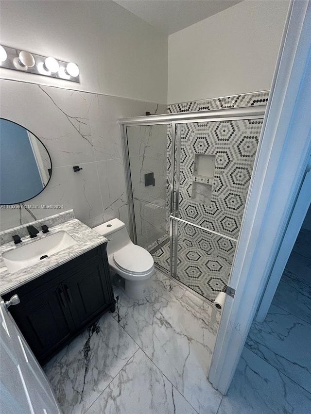 bathroom featuring vanity, toilet, tile walls, and a shower with shower door