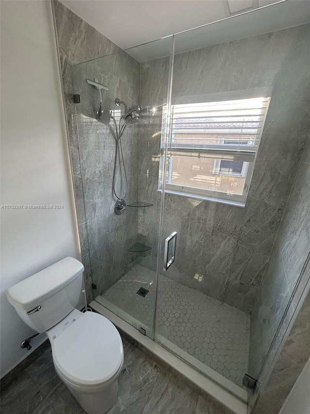 bathroom with a shower with shower door and toilet