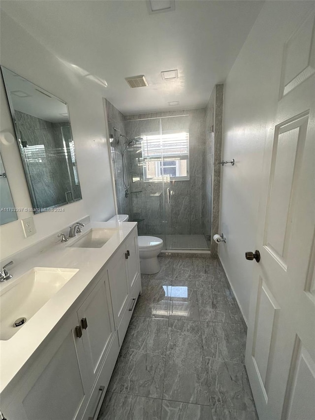 bathroom featuring vanity, a shower with shower door, and toilet