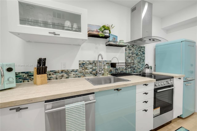 kitchen with white cabinetry, sink, stainless steel appliances, wall chimney range hood, and tasteful backsplash