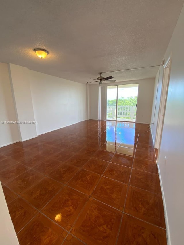 tiled spare room with a textured ceiling and ceiling fan