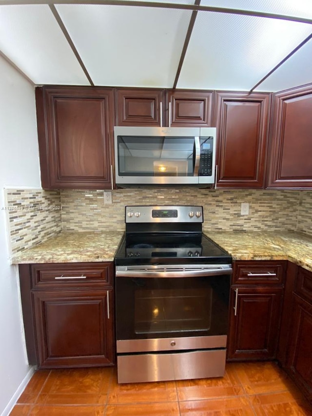 kitchen featuring decorative backsplash, appliances with stainless steel finishes, and light stone counters