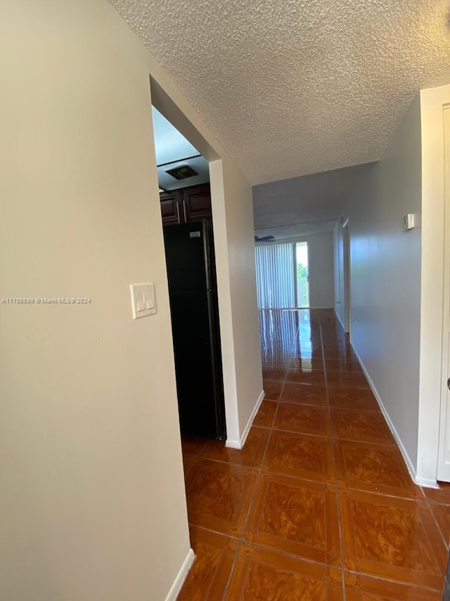 hallway with dark tile patterned floors and a textured ceiling