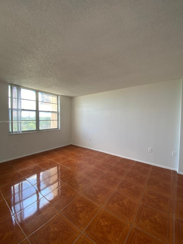 tiled empty room featuring a textured ceiling