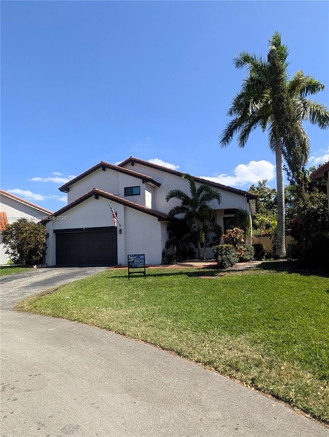 view of front facade featuring aphalt driveway, a front lawn, an attached garage, and stucco siding