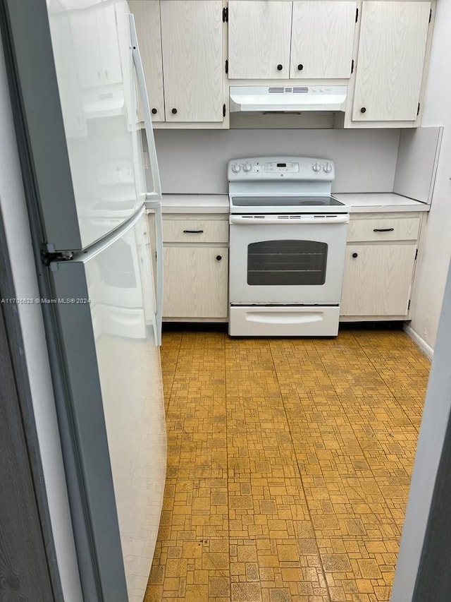 kitchen with white cabinets, range with electric cooktop, white fridge, and range hood