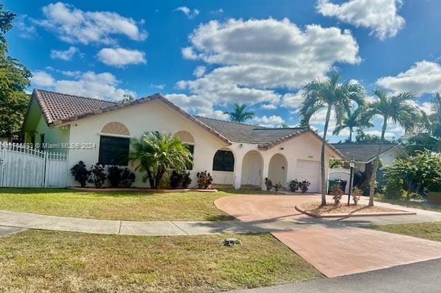 mediterranean / spanish-style home featuring a garage and a front lawn