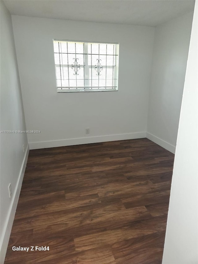 unfurnished room with dark hardwood / wood-style flooring