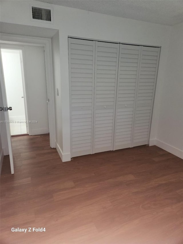 unfurnished bedroom with a closet, wood-type flooring, and a textured ceiling