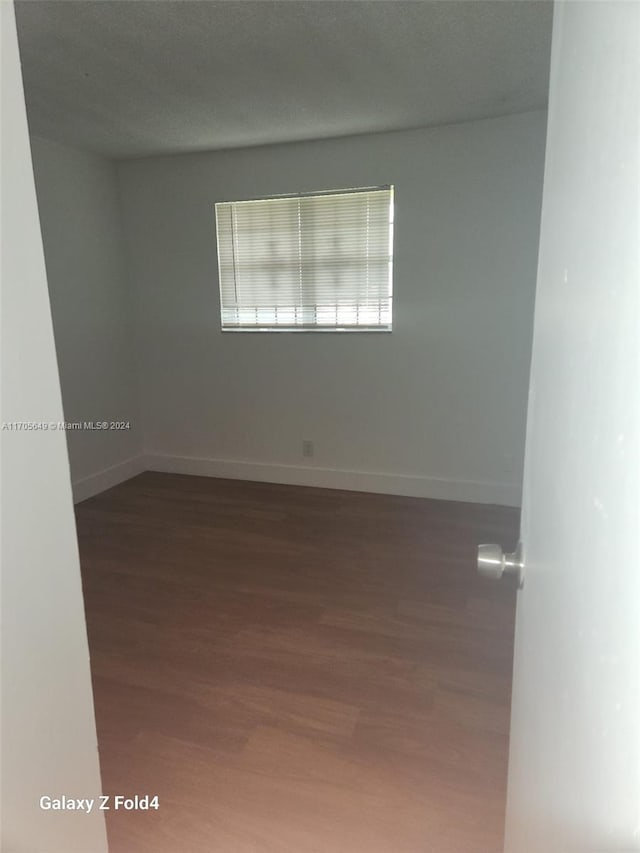 spare room featuring dark hardwood / wood-style floors and a textured ceiling