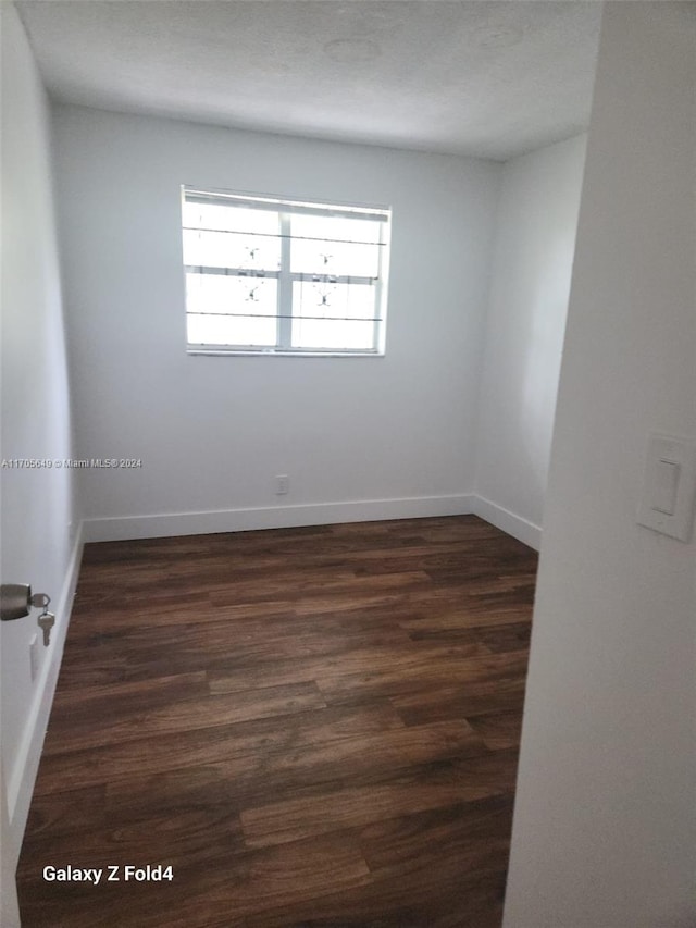 empty room featuring dark hardwood / wood-style floors and a textured ceiling