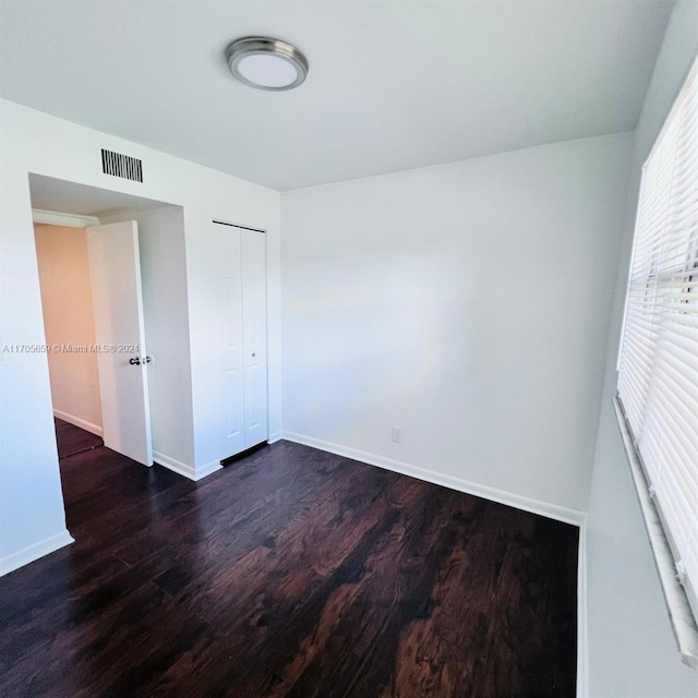 unfurnished bedroom featuring a closet and dark hardwood / wood-style floors