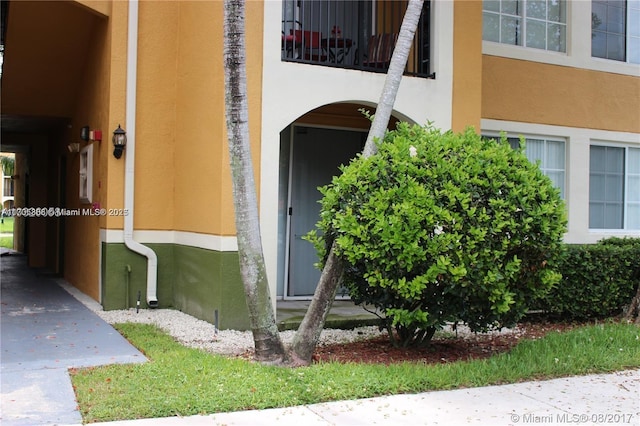 view of exterior entry with a balcony and stucco siding