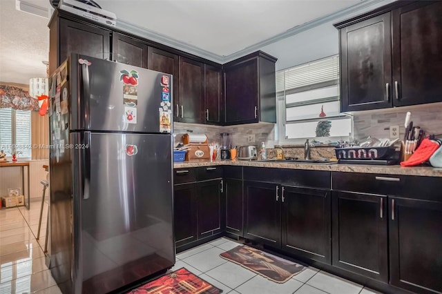 kitchen with stainless steel refrigerator, sink, light tile patterned floors, and ornamental molding